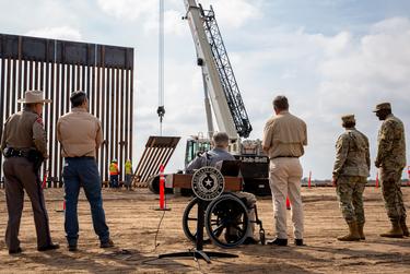 Gov. Greg Abbott looks at crane lifting a section of the border wall in place after giving a press conference at Rio Grande City on Dec. 18, 2021.