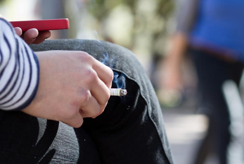 English student Kristin Miller smokes a cigarette and checks her phone on the South Mall between classes.