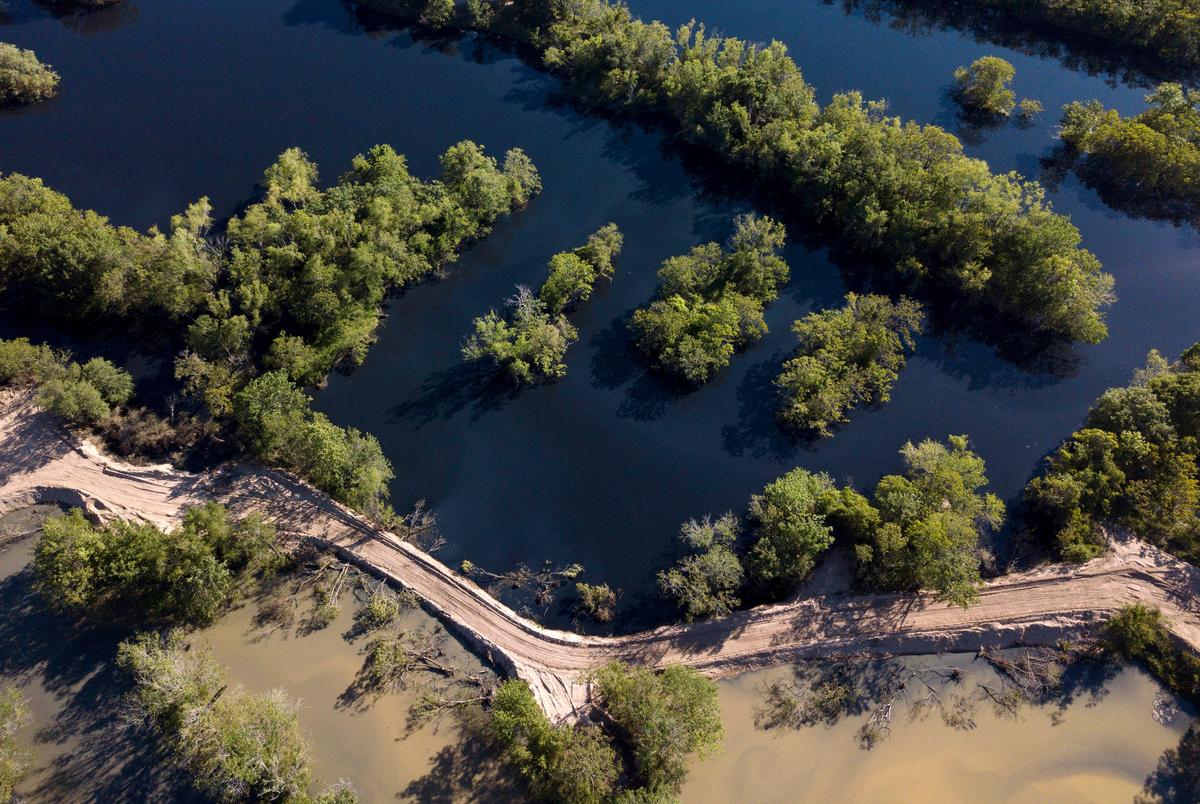 Earthen dams separate black water (top)  from muddy water (bottom) at Inland Environmental & Remediation, Inc., south of Columbus, Texas, on April 14, 2019.