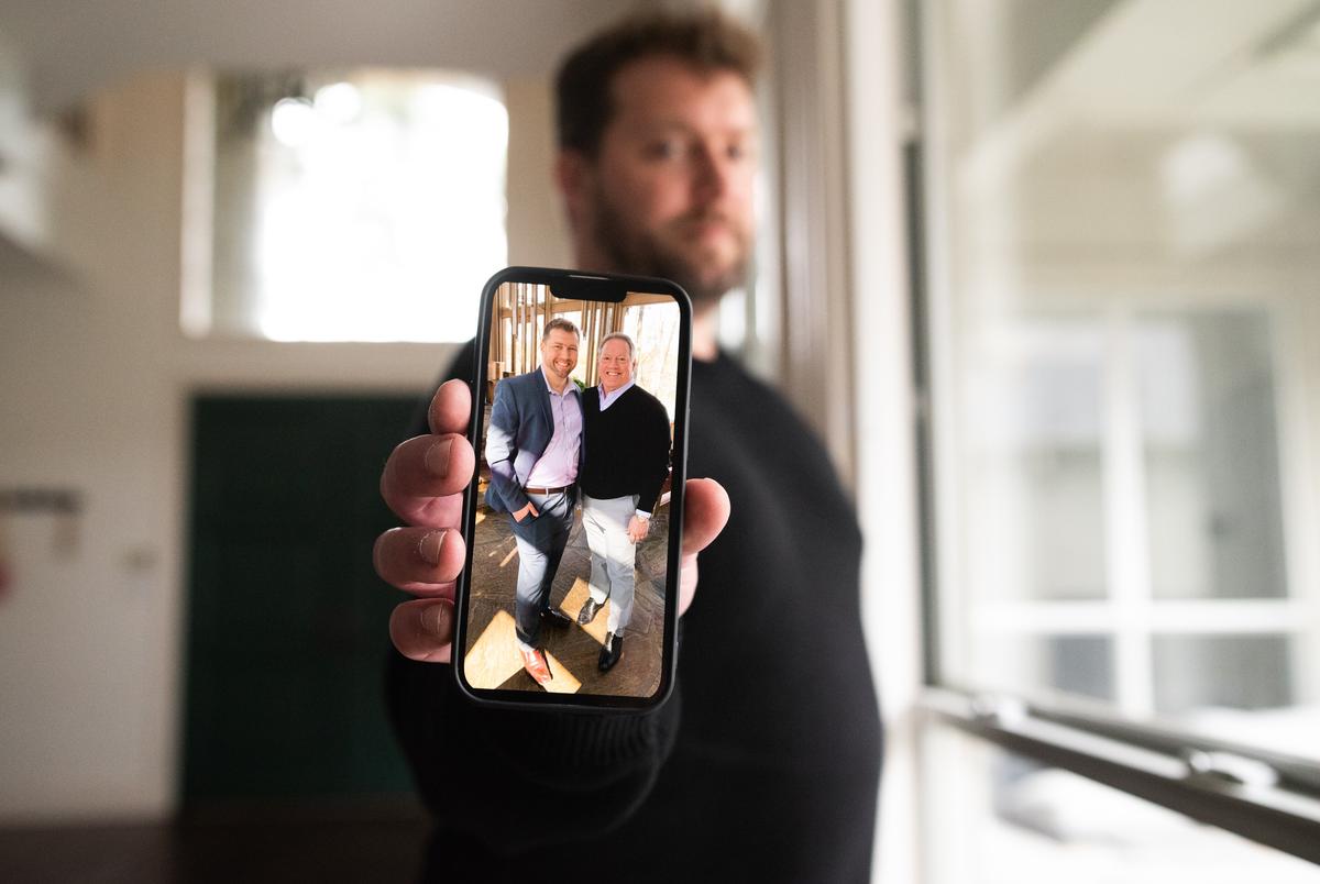 Jared Earles, 42, holds his iPhone showing a digital image of him and his father Brent Dean Earles, on March 21, 2022 at his home in Dallas. His father died from COVID-19 four days after his birthday.