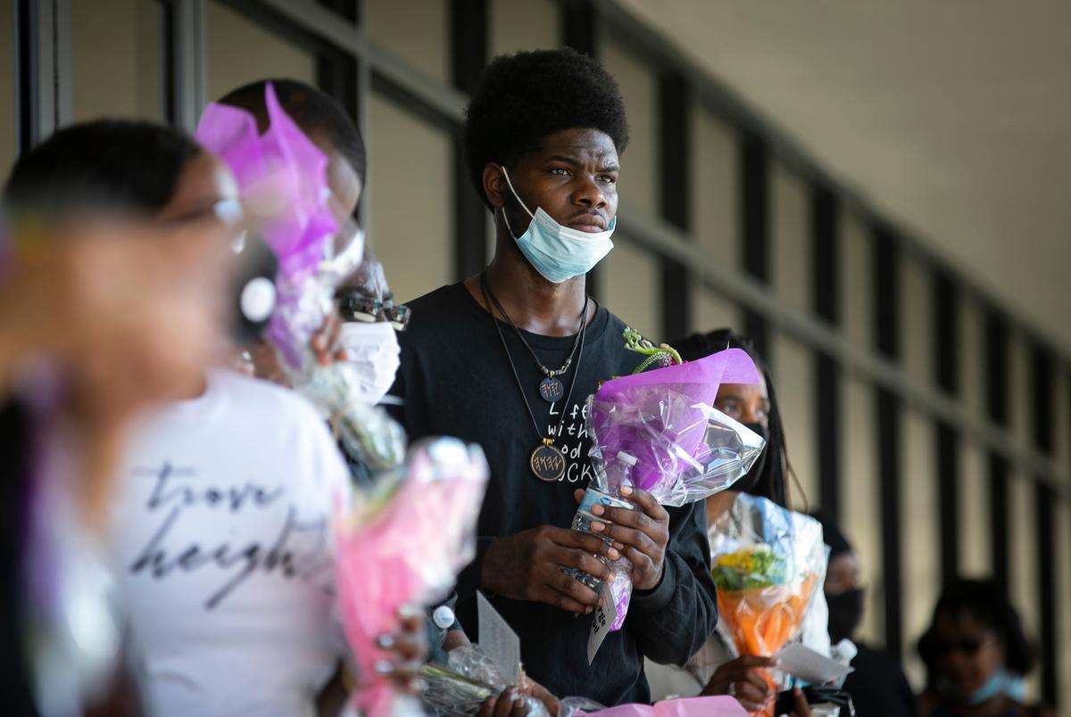 A man holds a bouquet of flowers at the Fountainlife Center as he waits in line to board a shuttle to the memorial for George Floyd in Houston on June 8, 2020.