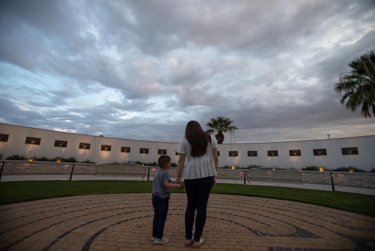 Jamie holds the hand of her son, Julian, as they visit the Healing Garden for the first time on Wednesday. Jamie worked at a bank inside Walmart in 2019 and witnessed the shooting just weeks before Julian was born.