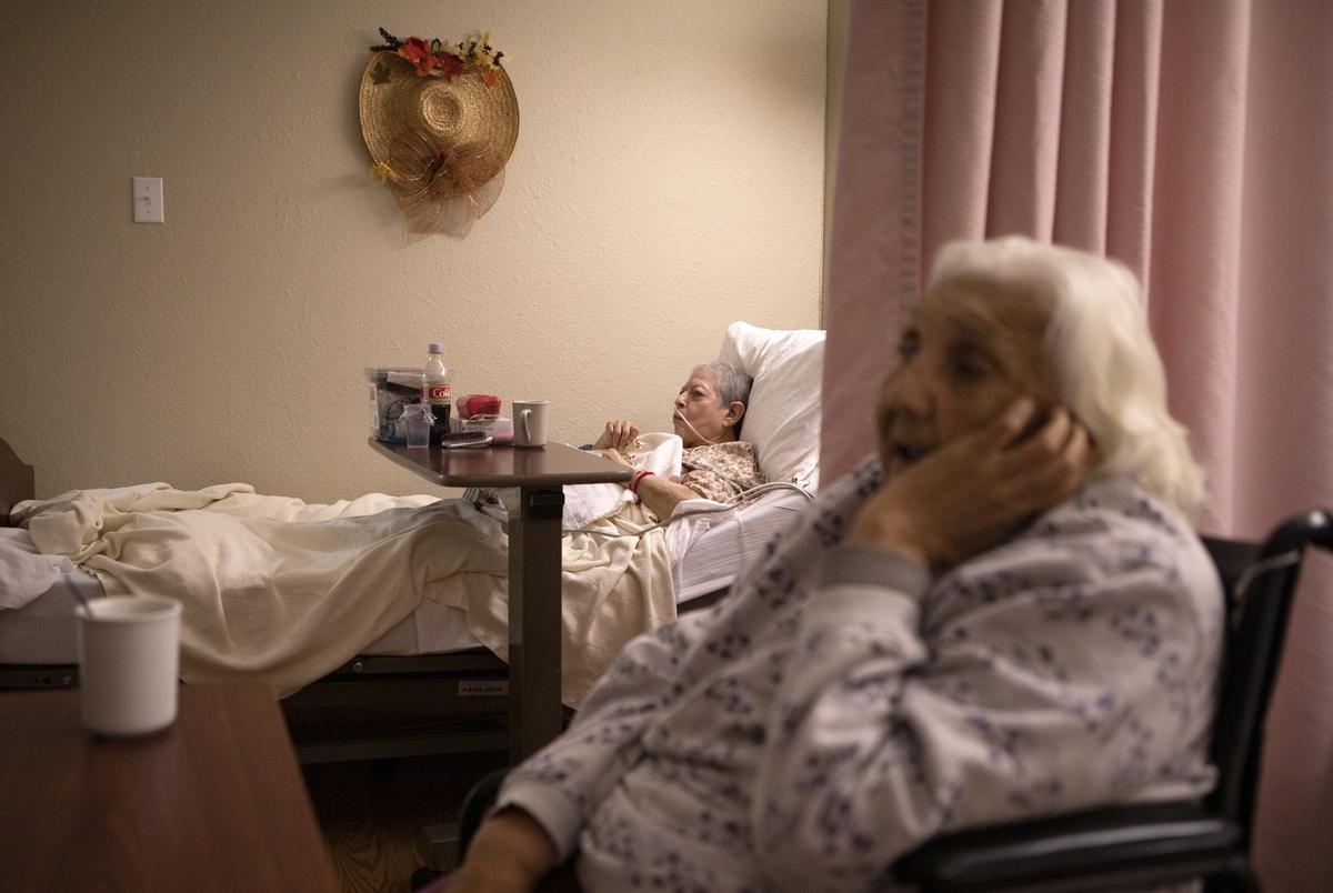 Rosa Ramos and Rebecca Pargas watch television while drinking coffee at the Amistad Nursing and Rehabilitation Center on April 1, 2021.