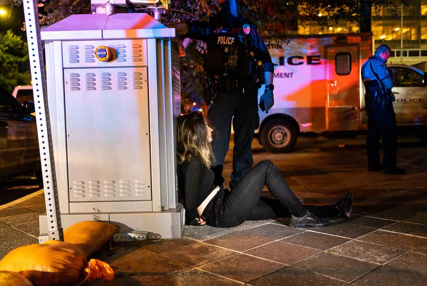 A woman in zip-tie handcuffs waits to be loaded onto a bus after being arrested during protests against police brutality in downtown Austin on Aug. 1, 2020.