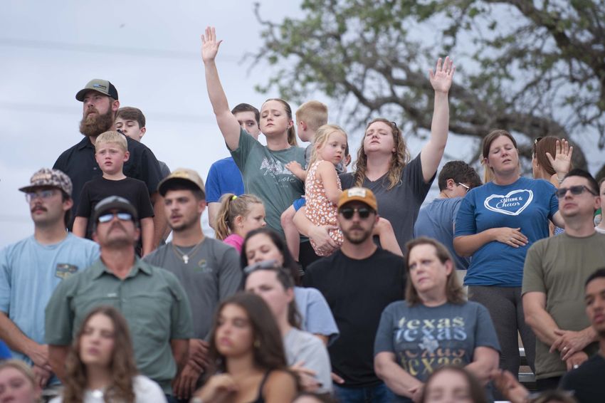 People pray during a Kerr County Blessing at Antler Stadium on Wednesday, July 9, 2025 in Kerrville, Texas.