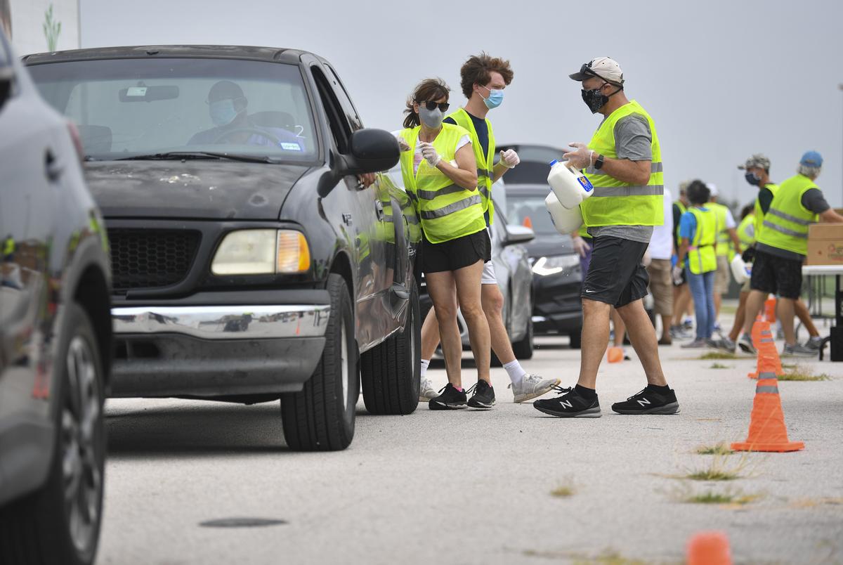 Volunteers load boxes of food into a car during a drive-thru food distribution hosted by the Central Texas Food Bank at the Travis County Expo Center on June 30, 2020 in Austin.