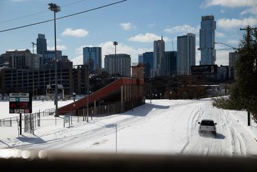 Vehicles attempt to drive through snow and ice on North Lamar Boulevard in Austin, Feb. 15, 2021.