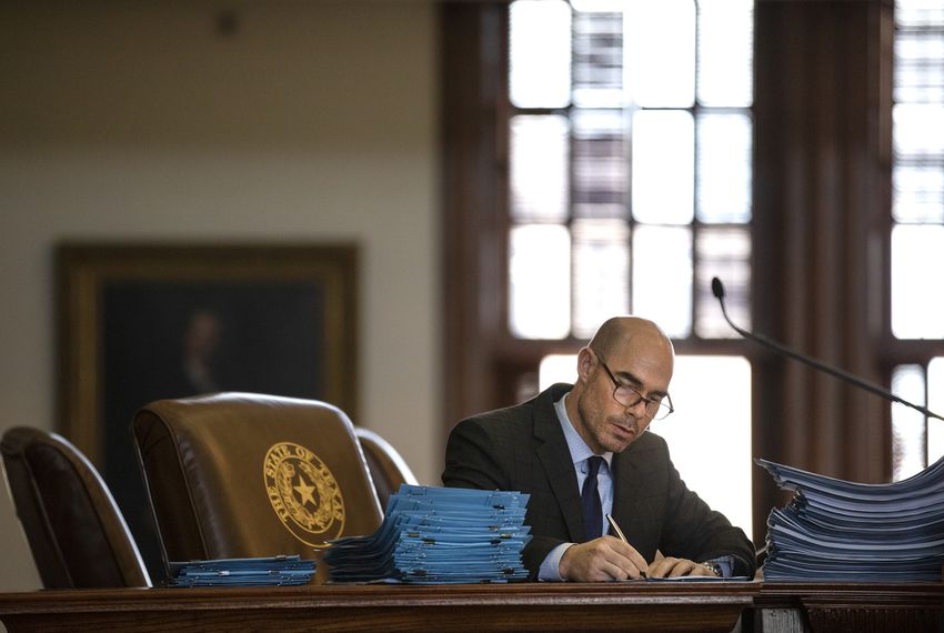 House Speaker Dennis Bonnen signs paperwork on the House floor.