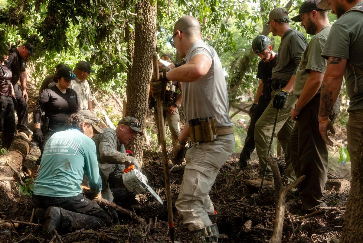 Law enforcement officials and volunteers clear up mountains of debris deposited by the flood in Center Point on Tuesday July 8, 2025.