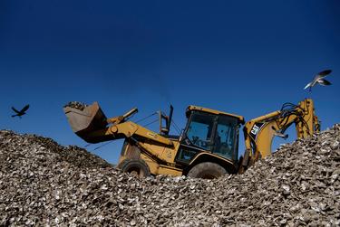 An employee of Misho's Oyster Company uses a backhoe loader to move oyster shells after the Texas Department of State Health Services ordered a recall for oysters harvested in the area of southeastern Galveston Bay in San Leon, Texas, U.S., on Thursday, December 15, 2022.