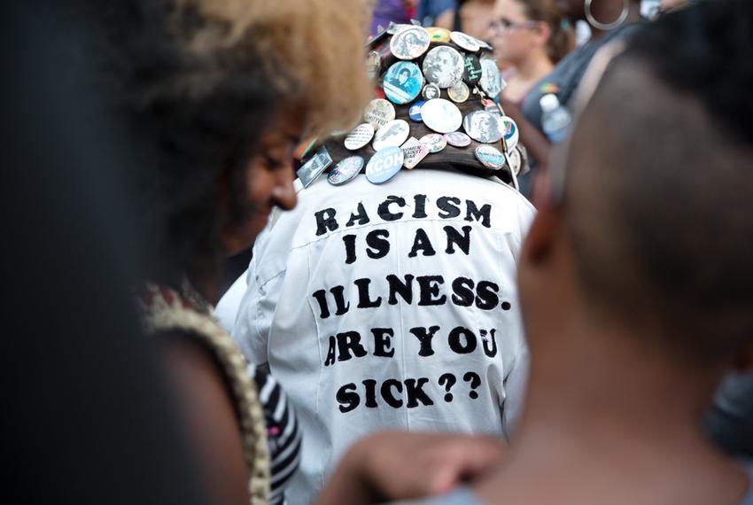 An attendee's shirt reads, "Racism is an illness. Are you sick?"