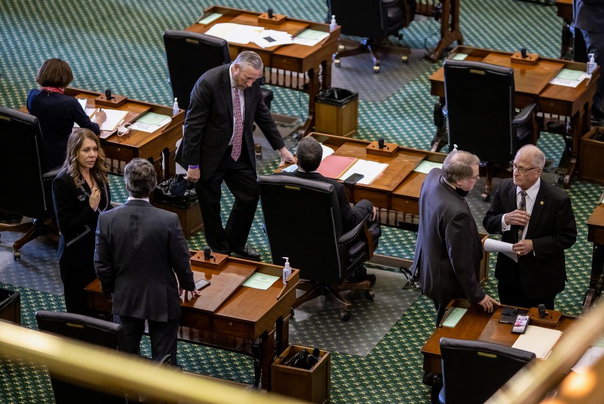 Maskless lawmakers speak to one another on the Senate floor prior to the session beginning on March 2, 2021.