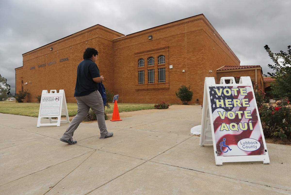 A voter walks past an election sign on his way to vote at Cavazos Middle School in Lubbock on  Nov. 8, 2022.