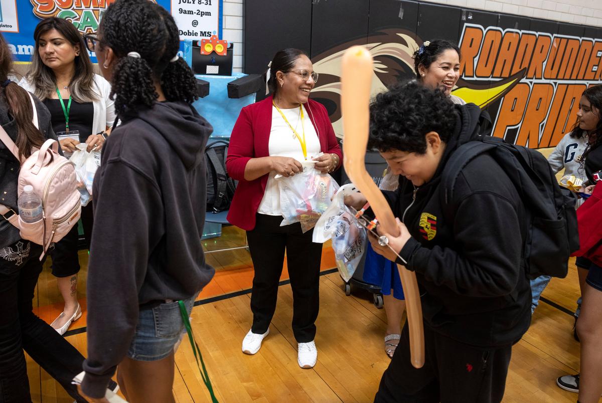AUSTIN, TEXAS - July 24, 2025: Carmen Mendoza hands out gift bags to campers as they head home. Austin Voices for Education and Youth hosts a summer camp at the Dobie Middle School for students that attend the three Austin ISD schools at risk of closure. Ilana Panich-Linsman for The Texas Tribune