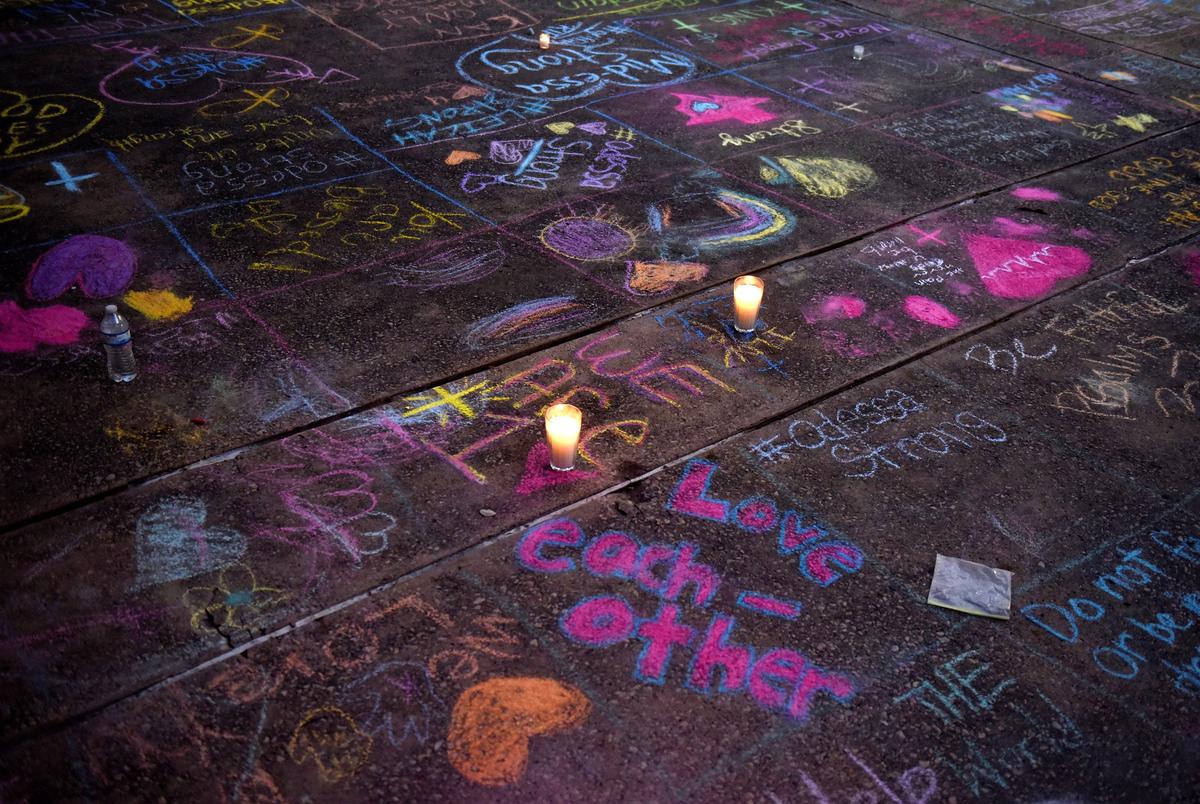 Messages were written in sidewalk chalk as people gathered for a vigil following the mass shooting in Odessa.