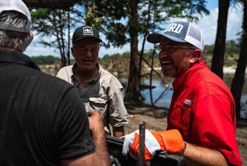 Cord Shiflet, right, jokes with volunteers while aiding in cleanup and recovery efforts at Camp CAMP, a summer camp for people with disabilities by Children's Association for Maximum Potential, following the Kerr County flood on Friday, July 11, 2025, in Center Point.