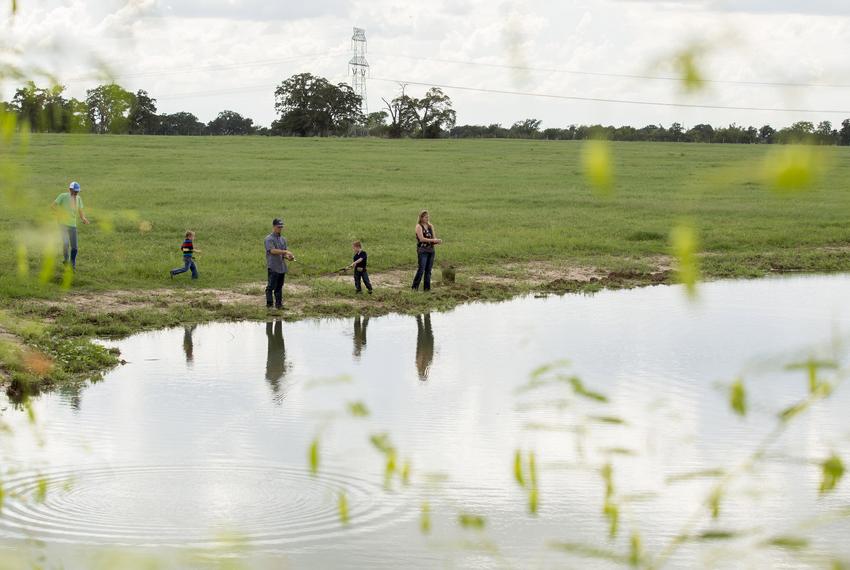 Randa and Charlie Calhoun with their twin sons, Cainen and Cash, 5, fish on their land in Bedias, Texas, on Sept. 15, 2018. The proposed high speed rail would be built along existing power lines.