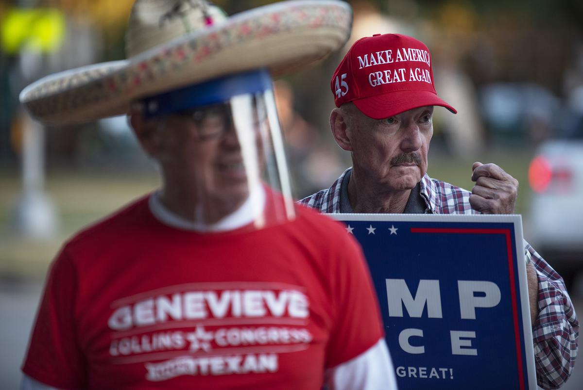 Jack Kennedy, right, sports a Make America Great Again cap while holding a Trump-Pence sign outside of the polling location at University Park United Methodist Church in Dallas on Nov. 3, 2020.
