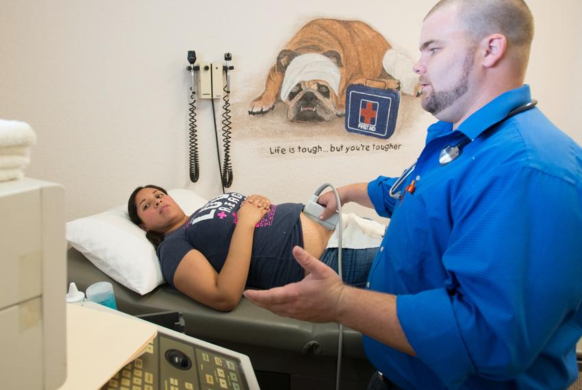 Dr. Brad Faglie, one of the family physicians being denied hospital privileges at the nearby Wise Regional Health System, examines Adriana Zuniga, a pregnant Medicaid patient at a medical clinic in Alvord.