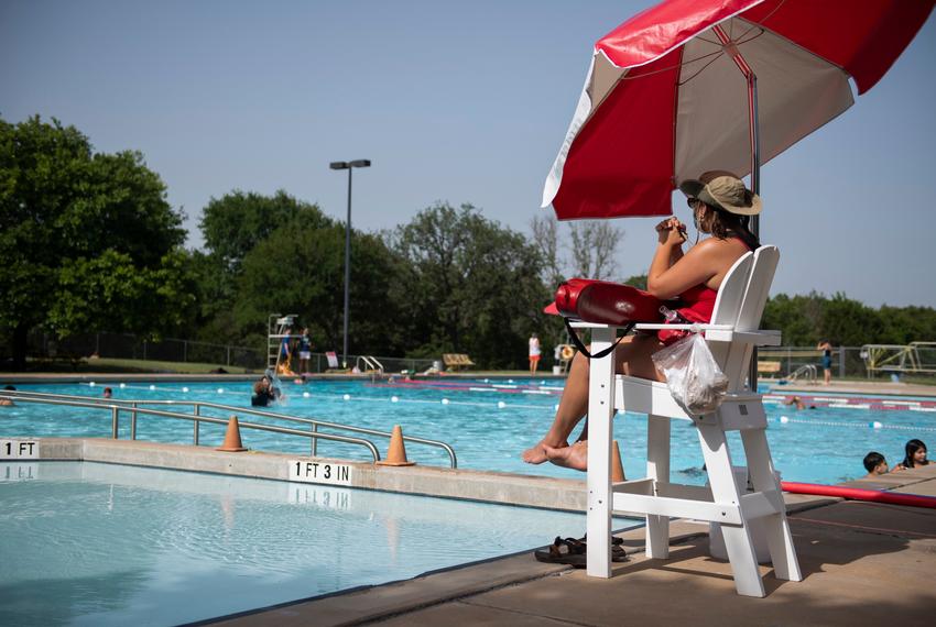 A lifeguard, wearing a face mask, watches people at a public pool in Austin on July 2, 2020. The City of Austin plans to close all city parks, pools and recreational facilities over the fourth of July weekend.