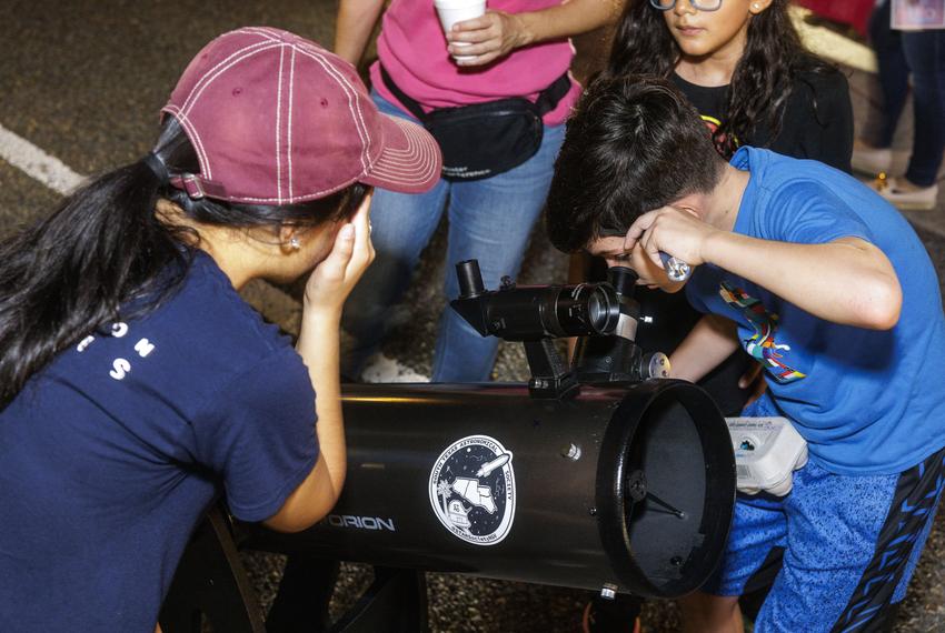 Staff members from the South Texas Astronomical Society  organization oversee a telescope setup for passersby to see stars at a night market in Brownsville on Sept. 20, 2025.