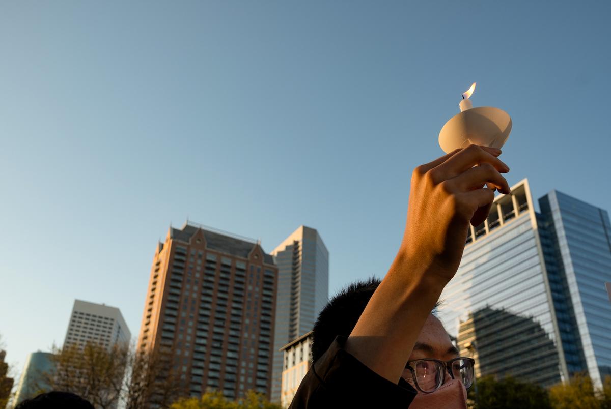 A person holds a candle skyward during a rally at Discovery Green on March 20, 2021, in Houston. People gathered for the Stop Asian Hate Vigil and Rally after a man killed eight, including six Asians, in a mass shooting at three Atlanta spas.