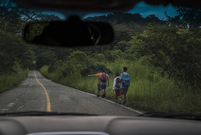 Migrants walk through Highway México 307 on Oct. 21 near Palenque, Chiapas. The highway is also known by the locals as 'El gran corredor del pacífico del migrante," or "The Great Pacific Corridor of the Migrant." This is a common route for Honduran migrants due to the proximity to their country.