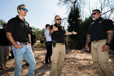 Texas attorney general candidate George P. Bush listens to National Border Patrol Union Local 2455 members Chris Cabrera and Oscar Vela as they explain how the area is monitored on Dec. 9, 2021, during a visit to a known illegal crossing site behind City Ready Mix in Laredo, as part of a border tour in South Texas.