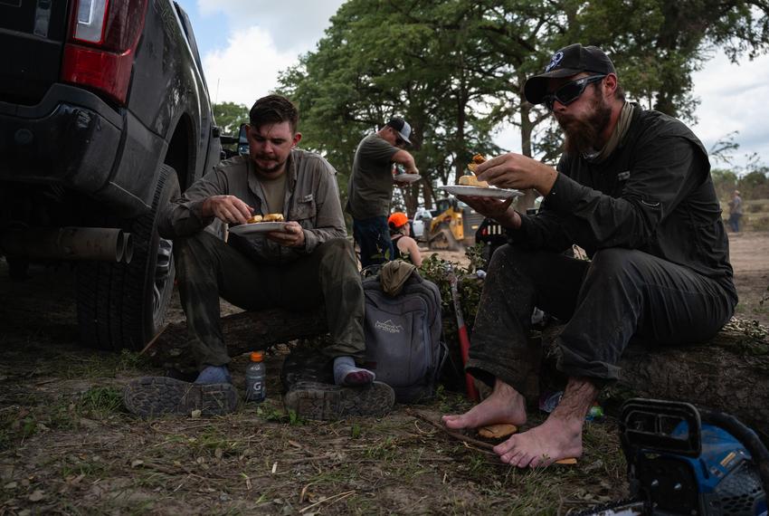 Volunteers air out their feet as they enjoy a hot meal during while assisting in recovery efforts at Camp CAMP, a special needs summer camp organized by Children's Association for Maximum Potential, Friday, July 11, 2025, in Center Point.