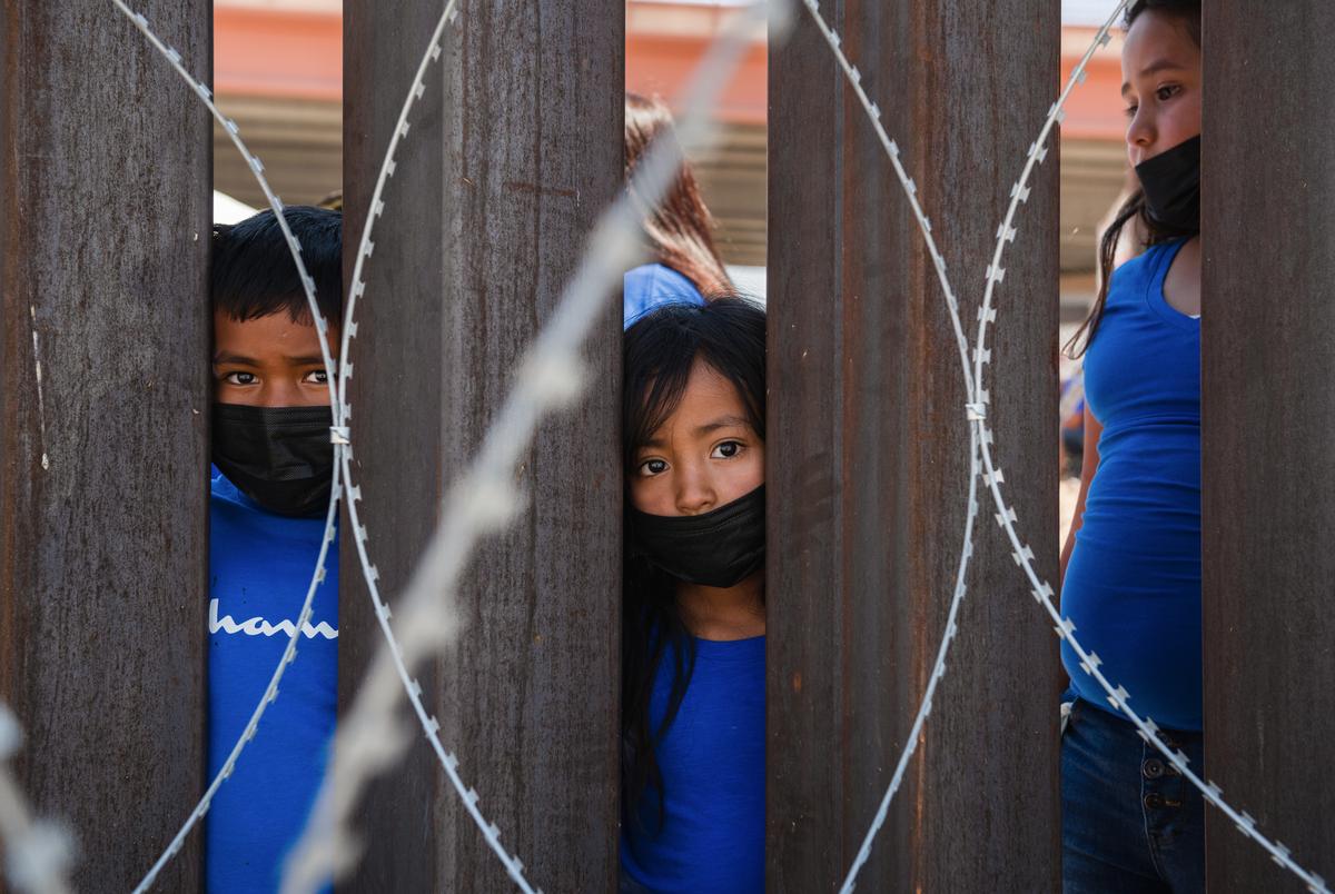 Children look through the border wall to their family in Ciudad Juarez, Mexico from El Paso, Texas on June 19, 2021.