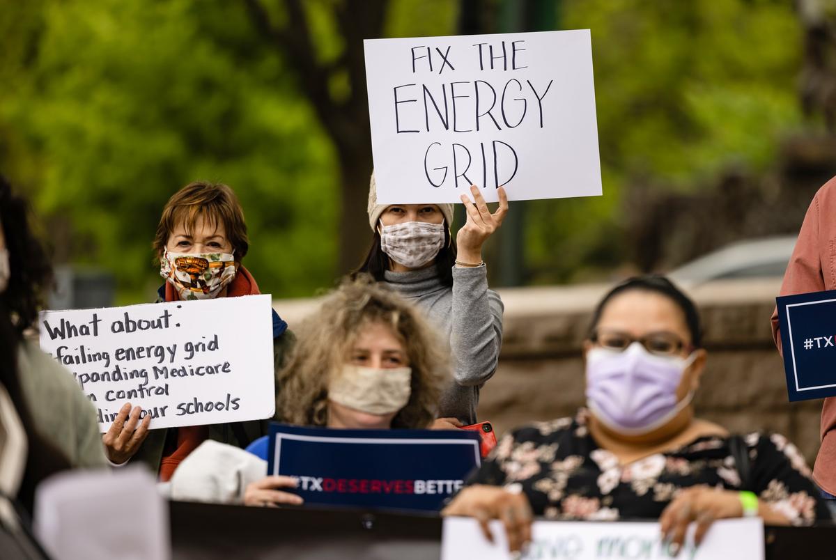 Activists hold signs advocating for improvements to Texas’ energy grid at a progressive rally at the south gate of the Capitol on April 22, 2021.