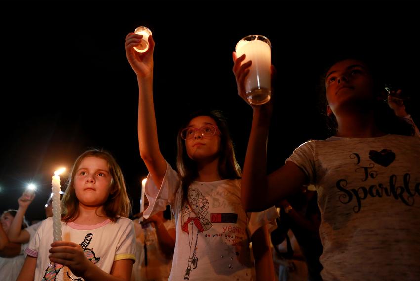 Mourners take part in a vigil near the border fence between Mexico and the U.S after a mass shooting at a WalMart store in El Paso on Saturday night after the shooting.