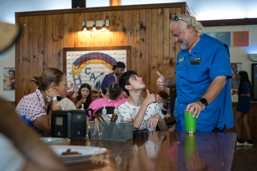 Brandon Briery, COO of Camp CAMP, gives a thumbs up to a camper, Adam, during breakfast on Tuesday, July 22, 2025, in Center Point.