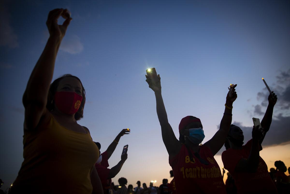 Candles are held up in the air during a vigil for George Floyd at Yates High School in Houston on June 8, 2020.
