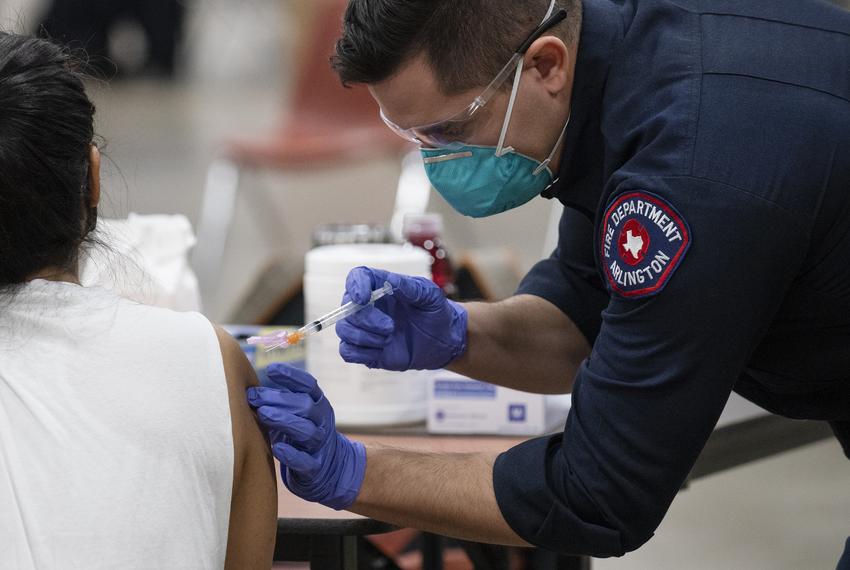 Arlington Fire Fighter Samuel Rochin, right, administered a COVID-19 vaccination to healthcare worker Vannia Atao, at the Es…