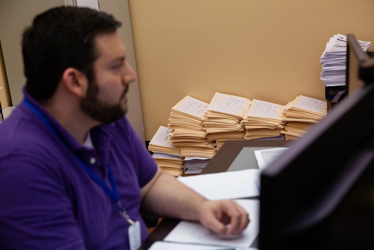 Epidemiologist Jason Geslois works at his desk at the Northeast Texas Public Health office in Tyler on Sep 22, 2020. Stacks of folders contain records and information of COVID-19 cases across seven counties in northeast Texas.