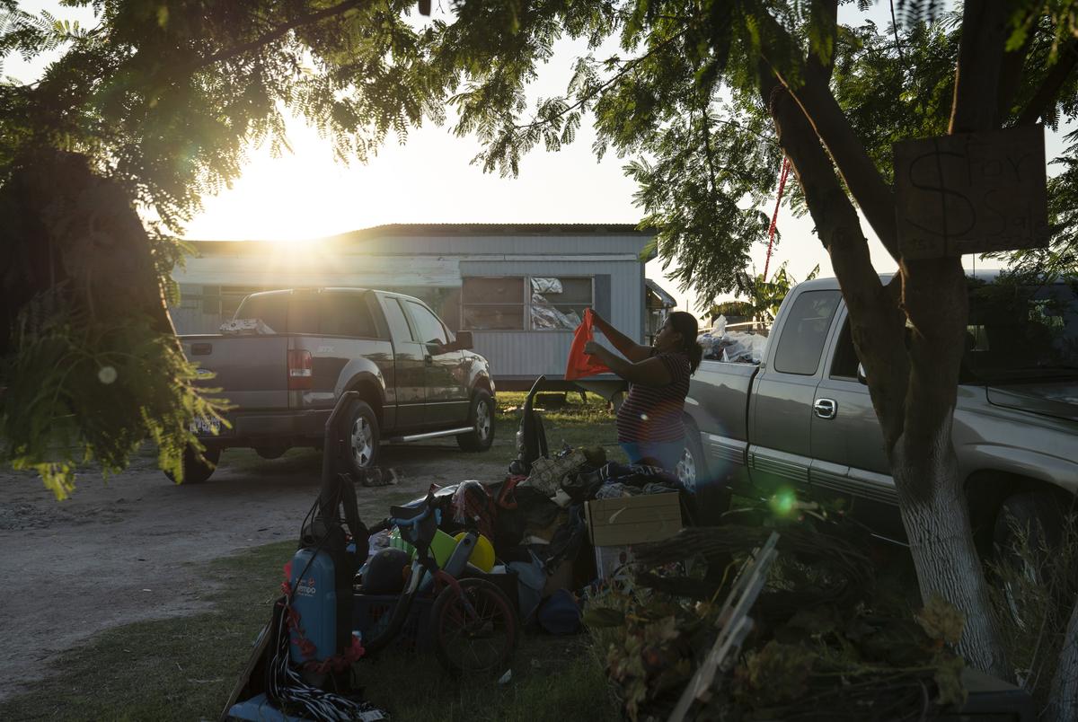 Liliana Ruiz, arranges used items in a garage sale that she is having outside of her house in a colonia in Edinburg.  Ruiz says that she called the census phone number to get her family counted. March 25, 2020.