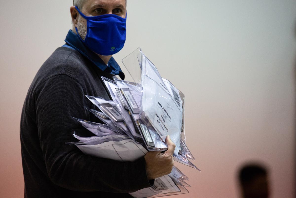 A Harris County election worker carries a stack of envelopes containing ballot information at NRG Arena on Nov. 3, 2020, in Houston.