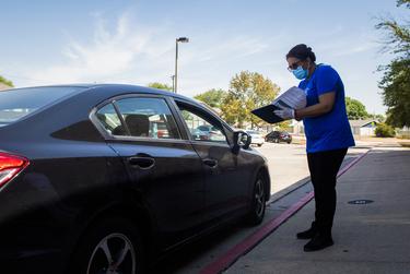 Round Rock ISD food service worker Angela Alba talks with a family during a curbside meal distribution at Bluebonnet Elementary School on Aug. 20, 2020 in Round Rock.