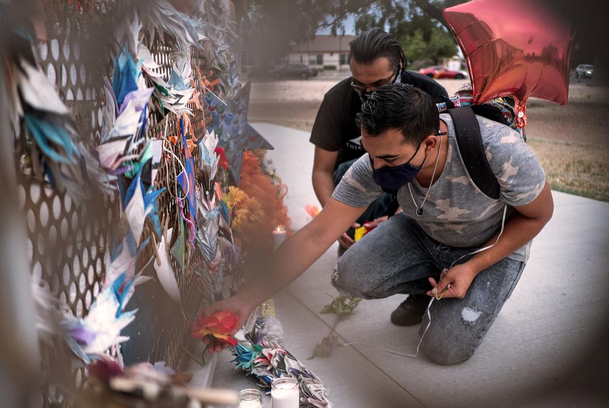 Isaiah Vale  places flowers at a memorial honoring the victims of the Walmart shooting at Ponder Park in El Paso.