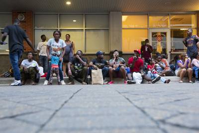 Migrants wait outside a makeshift center in downtown San Antonio where people are given food and a bag with basic hygiene products, then escorted to a nearby shelter to sleep for the night.