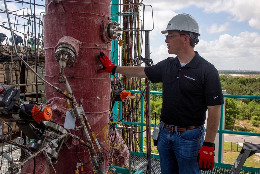 Patrick Hanks, chief technology officer of Graphitic Energy, pats the carbon formation vessel on the company’s San Antonio pilot project, which pulls solid carbon graphite out of methane gas.