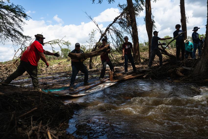 Volunteers form a bucket brigade to move flood debris from a pile formed in a portion of the Guadalupe River while assisting in recovery efforts at Camp CAMP, a summer camp for people with disabilities organized by Children's Association for Maximum Potential, Friday, July 11, 2025, in Center Point.