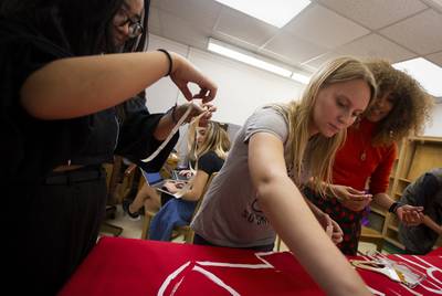 From left: Lynn Huynh, Shelby Hobohm and Simone Harry paint a banner for an upcoming protest during their Coalition Against Sexual Misconduct meeting on Dec. 3, 2019.