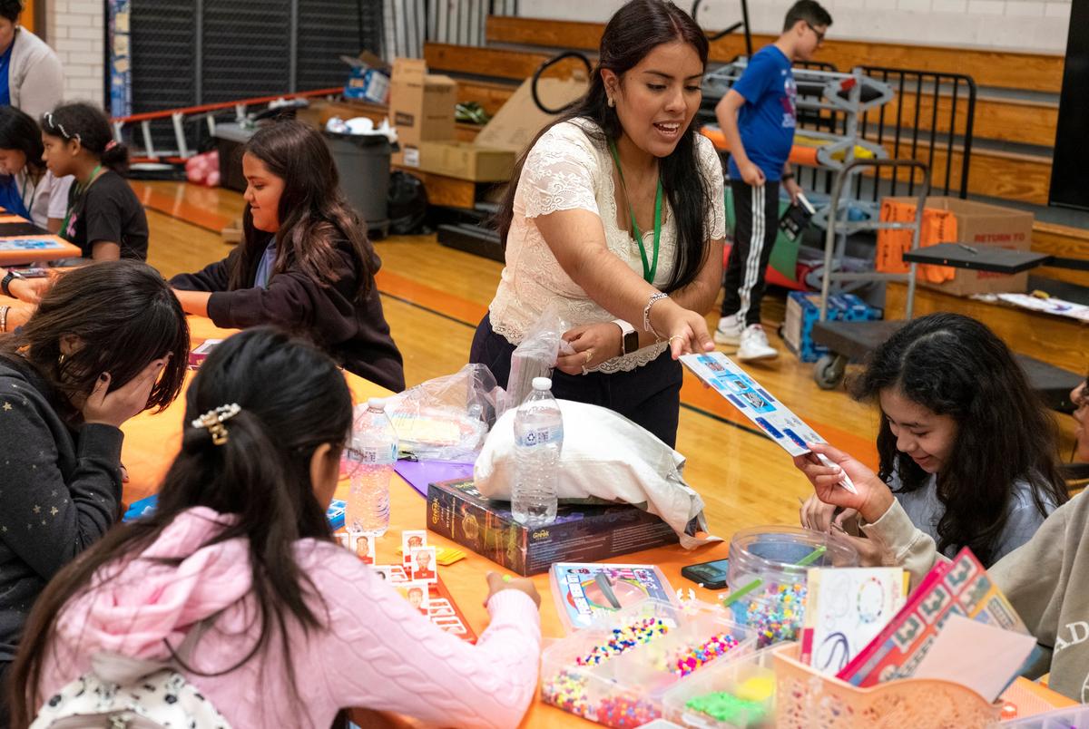 AUSTIN, TEXAS - July 24, 2025: Denisse Badillo, a promoter with Austin Voices, passes out cardboard robots to campers. Austin Voices for Education and Youth hosts a summer camp at the Dobie Middle School for students that attend the three Austin ISD schools at risk of closure. Ilana Panich-Linsman for The Texas Tribune