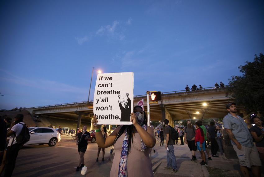 A protester holds a sign at a rally for George Floyd and Mike Ramos at Austin Police headquarters on May 30, 2020. 