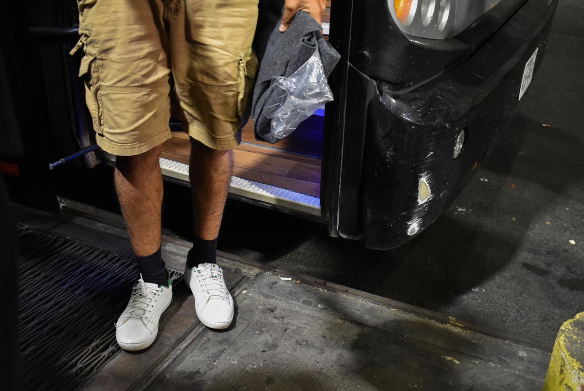 A migrant steps down from a chartered bus and makes his way to the inside of the Port Authority building.