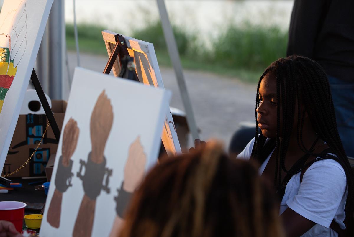 Trineese Potter paints at the Creative Tingz shop stand during the I Am Juneteenth festival at the Panther Island Pavilion in Fort Worth on June 19, 2021.