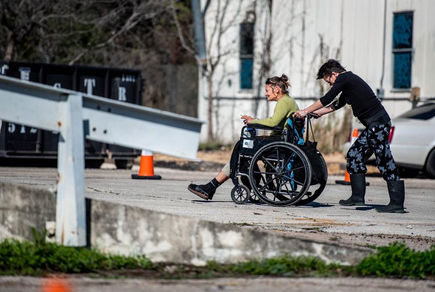 Amy T. pushes Pam Reynolds to her camping location on Jan. 23, 2020 at a state-sanctioned homeless camping site in Austin. Amy T. was helping Pam replaced her bedding after it soaked up during a rainstorm.