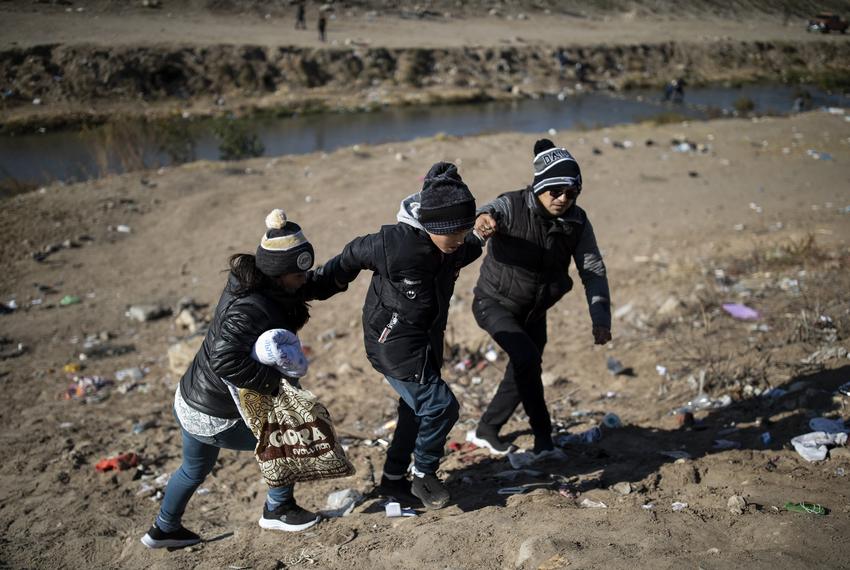 A migrant family holds hands after crossing the Rio Grande into El Paso from Ciudad Juárez on Monday, Dec. 19, 2022.